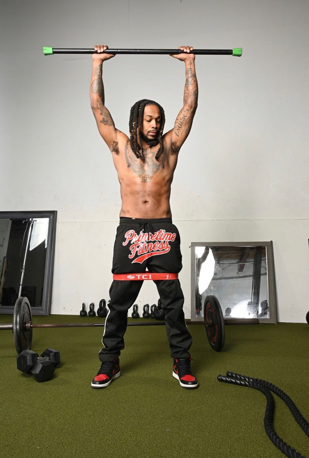 Coach Prime demonstrating a barbell and resistance band overhead press
